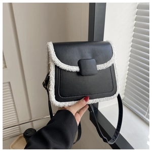 Detail of crossbody bag featuring black matte leather with white faux shearling trim accents