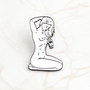 Detailed macro view of a minimalist black and white enamel pin with artistic female silhouette