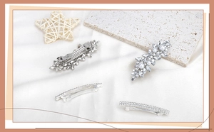 Close-up of four silver hair clips with marquise rhinestones and pearls on white silk