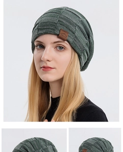Detailed close-up of dark green cable knit beanie with premium brown leather sports patch