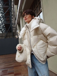 Women's cream puffer jacket with high collar and quilted design in urban street setting