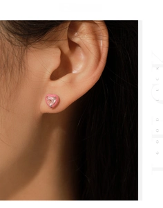 Close-up of s925 silver heart stud earrings with pink gemstone on model ear
