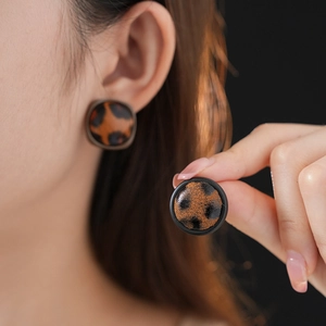 Gros plan d'un mannequin portant des boucles d'oreilles léopard rondes avec bordure noire