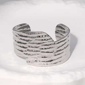 Macro shot of silver hammer texture on wide stainless steel open cuff bracelet