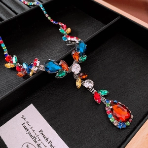 Detail of colorful water-drop and round zircon gems on a refined vintage leaf necklace