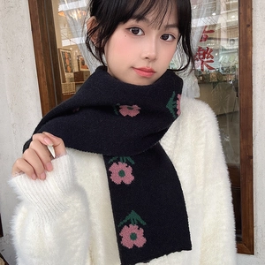 Detail of black knitted scarf with pink and green floral patterns on a female model