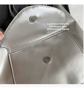Close-up of silver tote bag showing magnetic buckle closure and front pocket detail
