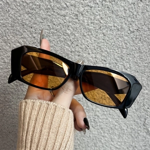 Detail of vintage rectangle sunglasses with glossy black frames and orange lenses