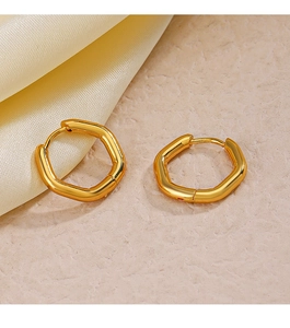 Vista macro di orecchini esagonali placcati oro 18K su tessuto di seta beige