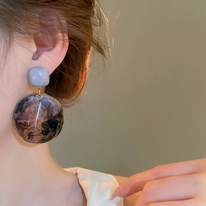Detail of irregular resin drop earrings with marble pattern on a fashion model