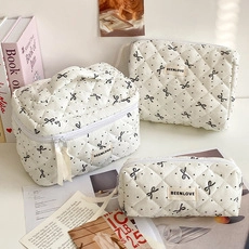 Three-piece set of white quilted cosmetic bags with black polka dots and butterfly prints