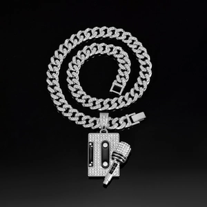 Silver cuban link chain with iced-out cassette and microphone pendants on black surface