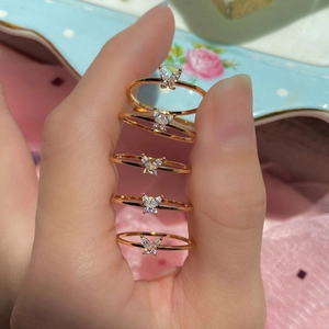 Detailed view of hand wearing five gold butterfly rings with clear zircon stones