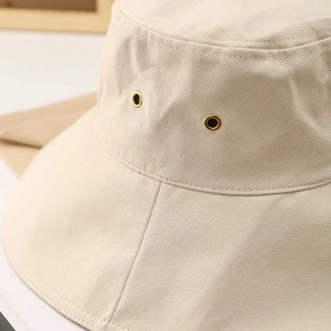 Detailed close-up of beige sun hat fabric showing metal eyelets and stitching