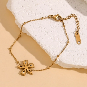 Detail eines 18K vergoldeten Edelstahlarmbands mit Zirkon-Blumenanhänger auf Stein