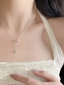 Detail of S925 silver Y-shaped necklace featuring teardrop sapphire and small bell pendant