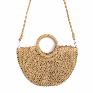 Detail of hand-woven straw crossbody bag with round handle and braided strap for beach