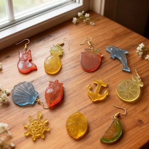 Detail of colorful resin earrings in fruit and animal shapes on a warm wooden background