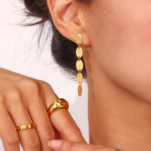 Gros plan sur des boucles d'oreilles ovales et bagues plaquées or 18K sur un modèle