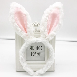 Cute white and pink plush rabbit ears headband displayed on a minimalist photo frame