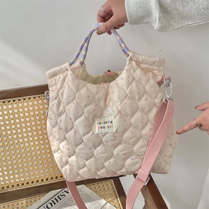 Close-up of pink quilted crossbody bag with cute rabbit prints and woven handle