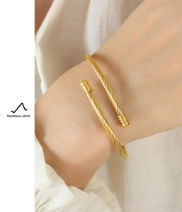 Close-up of a gold-plated stainless steel spiral cuff bracelet worn on a female wrist