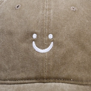 Vintage khaki washed cotton baseball cap featuring a white embroidered smiley face design