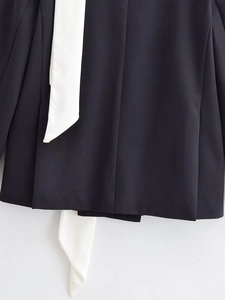 Detail of black blazer featuring white contrast scarf drapes and woven fabric texture