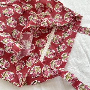 Detail view of red floral block print tote bag with white zipper closure and lining