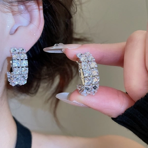 Detail of silver C-shaped hoop earrings featuring multi-row inlaid sparkling zircons