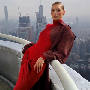 Détail d'une robe longue moulante rouge portée avec un trench-coat marron classique en ville