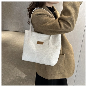 Close-up of white plush fleece tote bag featuring brown leather fashion label and slim strap