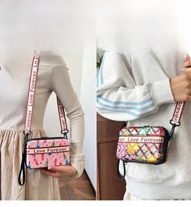 Détail d'un mini sac bandoulière gaufré avec plumes roses et motifs graffiti abstraits