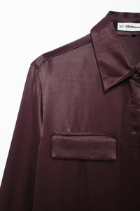 Detail view of deep purple satin shirt featuring lapel collar and chest pocket texture