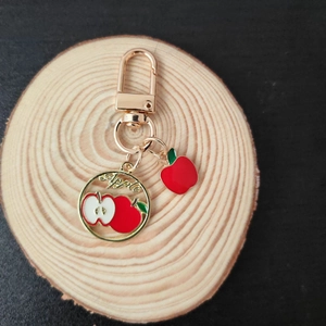 Detailed view of a gold keychain featuring a stylized apple charm and round apple pendant