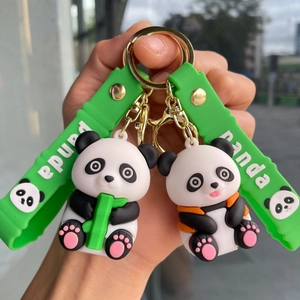 Close-up of cute panda keychains with green straps and gold hardware for backpacks