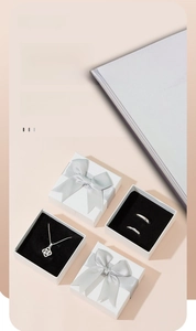 Detailed view of white jewelry gift boxes with grey bow and black velvet interior lining