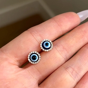 Close-up of gold-plated S925 silver evil eye stud earrings with blue micro-pave crystals