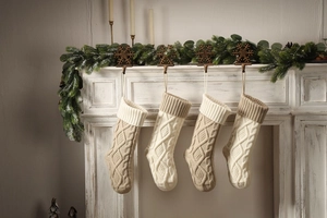Close-up of beige and white knitted Christmas stockings hanging on a white fireplace