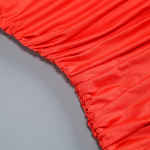 Detail of red ruched fabric texture on a slim fit one-shoulder party cocktail dress