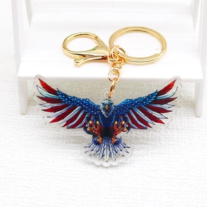 Acrylic American flag eagle keychain with gold metal clasp on a textured white surface