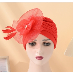 Detail of red turban hat with mesh flower, feathers and pearls on mannequin stand