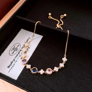 Close-up of 18k gold plated bolo bracelet with colorful stones and clover charms