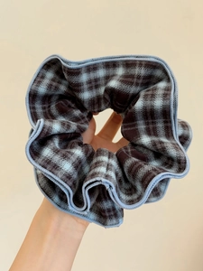 Close-up of blue and dark brown checkered fabric scrunchie with detailed stitching