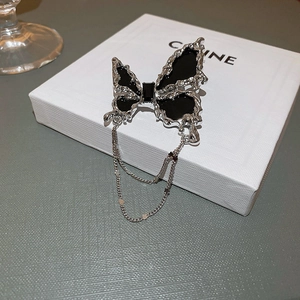 Détail macro de la broche papillon en métal liquide argenté avec zircon et pampilles