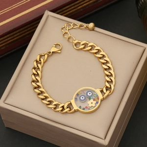Close-up of golden bracelet featuring a round charm with evil eye and colorful stones