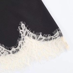 Close-up of black satin fabric with intricate cream lace trim and eyelash edge detail