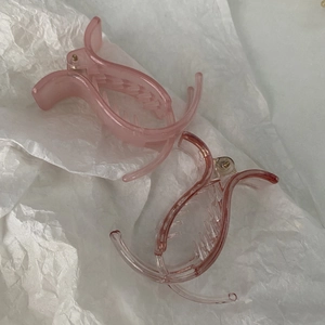 Close-up of matte and transparent pink 5cm hair clips on a soft textured background