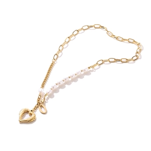 Dettaglio della collana con pendente a cuore dorato e catena mista metallo e perle bianche