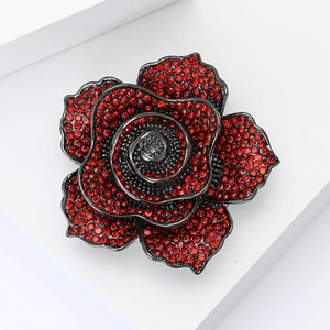 Vintage rose flower brooch with red rhinestones on a white geometric display stand